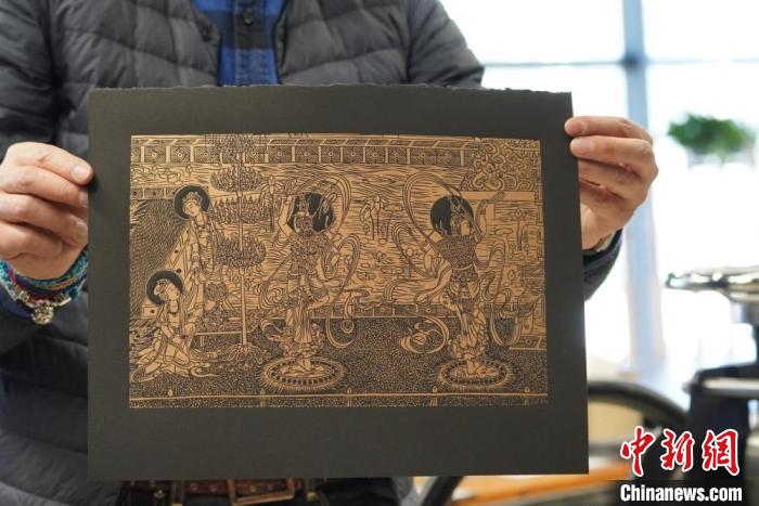 圖為手工書(shū)藝人展示敦煌雕版壁畫(huà)印刷品。　九美旦增 　攝