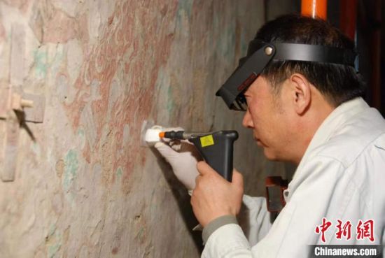 敦煌研究院研究員樊再軒進行壁畫修復(fù)。(資料圖)張云文 攝